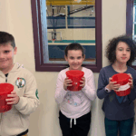 Three children holding small red buckets